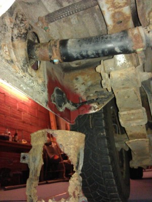 Rear left from inside. Tank pipe with rust holes, formerly mud filled &quot;protector&quot; lying beneath.